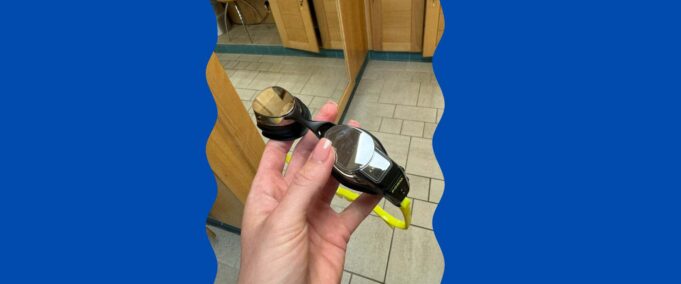 FORM smart goggles held in a persons hand in the changing room of the swimming baths.