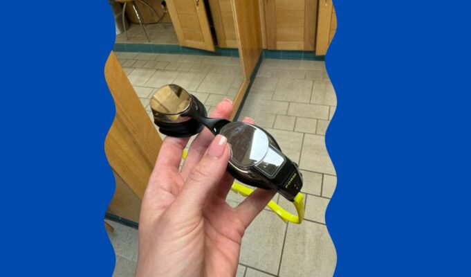 FORM smart goggles held in a persons hand in the changing room of the swimming baths.
