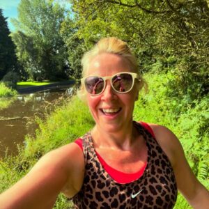Woman runs alongside canal wearing bright red sports bra under an animal print vest