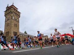 Many runners pass in front of a large tower