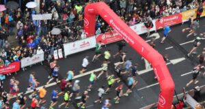 Cardiff half marathon runners running under a red inflatable gantry