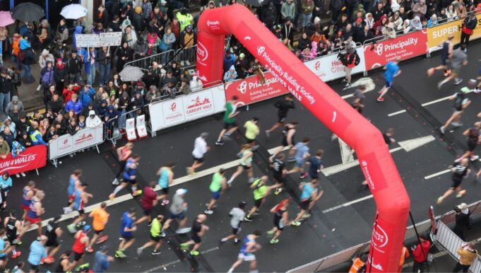 Cardiff half marathon runners running under a red inflatable gantry