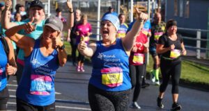 Two runners wearing mind running vests holding their thumbs up for the camera whilst running