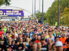 start of the manchester half marathon 2024. Lots of runners heading out on to the course with a large good luck banner in the background