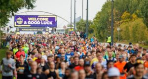 start of the manchester half marathon 2024. Lots of runners heading out on to the course with a large good luck banner in the background