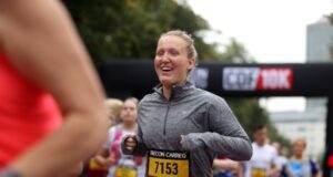 Female runner in grey long sleeve top smiles broadly