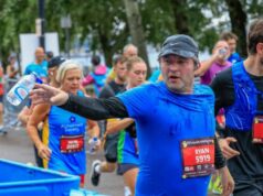 Male runner in blue top tosses water bottle into a blue bin