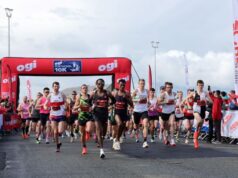 Lots of male runners under a red race gantry