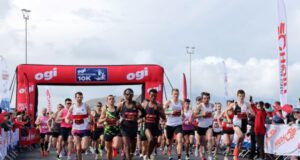 Lots of male runners under a red race gantry