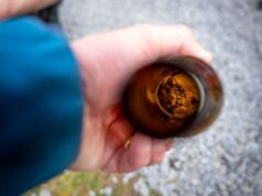 A small mouse is asleep inside a glass bottle