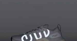 A grey running shoe with reflective detail against a grey background