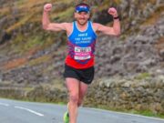 Man in vest and shorts runs with arms in the air