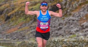 Man in vest and shorts runs with arms in the air