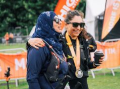 Two women at the end of an ultramarathon smile, their arms around one another
