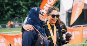 Two women at the end of an ultramarathon smile, their arms around one another