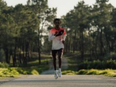 Male athlete runs towards camera on a tree lined road