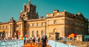 Triathletes run through a transition area with bikes in front of a spectacular palace