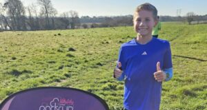 Boy in blue tshirt poses with thumbs up, next to sign saying Upton House.
