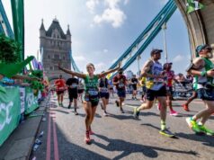 Runners cross over Tower Bridge on a sunny day