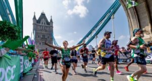 Runners cross over Tower Bridge on a sunny day