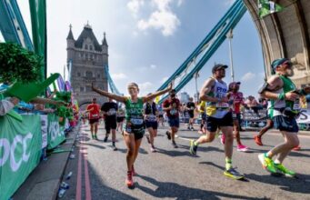 Runners cross over Tower Bridge on a sunny day