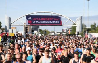 Thousands of runners in the start area of Manchester Marathon, under a banner which reads UK's largest day of marathon running