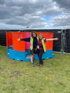 Two women stand in front of a booth designed for women to pee standing up