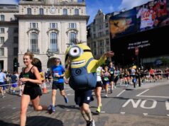 Peron dressed up as a minion runs alongside a female runner in black on a London street