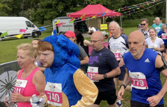 Runners in a race on grass all wearing pink race numbers