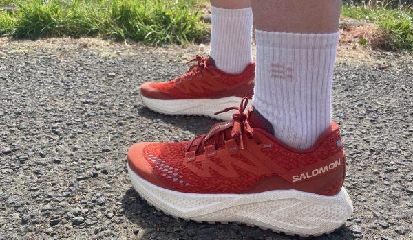 Red shoes with a thick white sole pictured on the feet of a runner wearing white socks