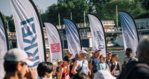 Runners wearing sashes line up at a start lined with flags
