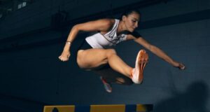 Woman jumps over a hurdle in a dark room