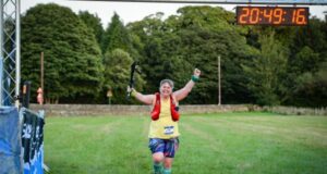 A female runner looks ecstatic to be crossing the finishing line