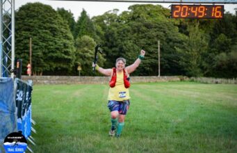 A female runner looks ecstatic to be crossing the finishing line