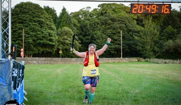 A female runner looks ecstatic to be crossing the finishing line