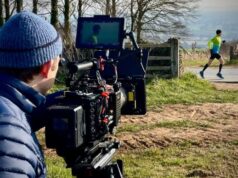 View from behind a camera man as he films a runner passing ahead