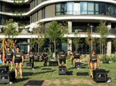 Men and women use an outdoor gym outside a hotel in a sunny location