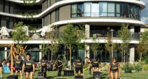 Men and women use an outdoor gym outside a hotel in a sunny location