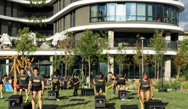 Men and women use an outdoor gym outside a hotel in a sunny location