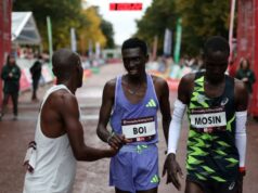 One man shakes another man's hand at a race finish line.