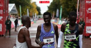 One man shakes another man's hand at a race finish line.
