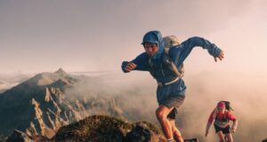 Two trail runners summit a high mountain