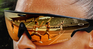 Close up of woman's face wearing large sunglasses. Female track athletes are reflected in them.