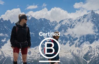 A male an female athlete stand on an alpine mountain top