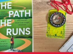 Photo shows copy of the Path She Runs on a wooden table next to a map and compass