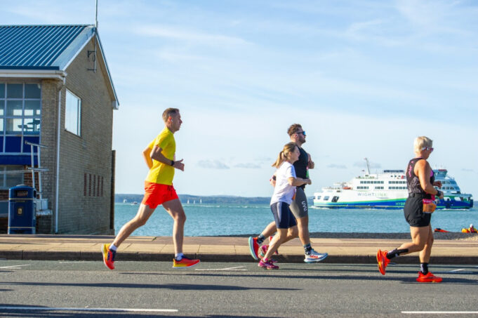 Runners by the coast with a boat in the background out to sea