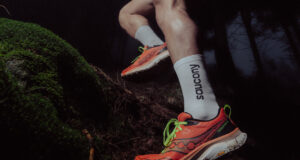 Close up of runner's feet in orange shoes stepping over a tree trunk