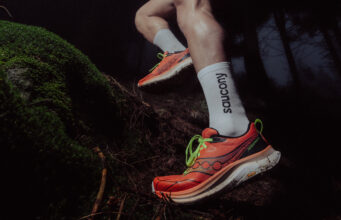 Close up of runner's feet in orange shoes stepping over a tree trunk