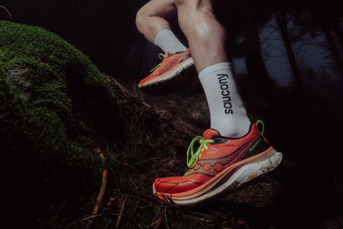 Close up of runner's feet in orange shoes stepping over a tree trunk