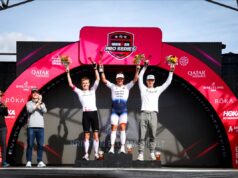 Three men stand on a podium with arms in the air in celebration